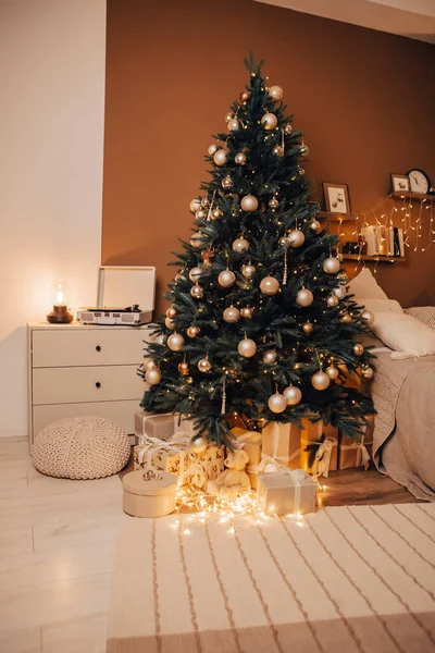 Stock image Vertical image of cozy flat apartment room green Christmas Tree gifts presents garlands, candles decorated toys balls interior New Year beautiful living room in the evening, lights glowing bokeh