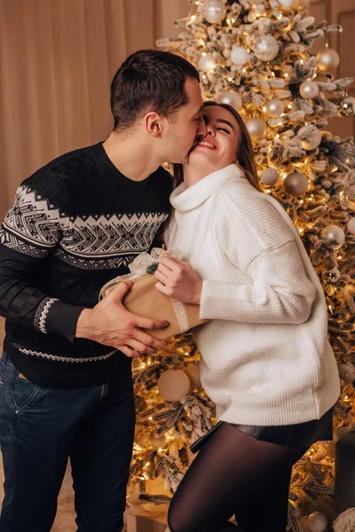 垂直画像素敵な若いロマンチックなカップルがオープンギフトに座っているプレゼントガーランドホーム居心地の良いインテリア雰囲気新年クリスマスツリーの装飾休日パーティー冬の夜を祝う — ストック写真