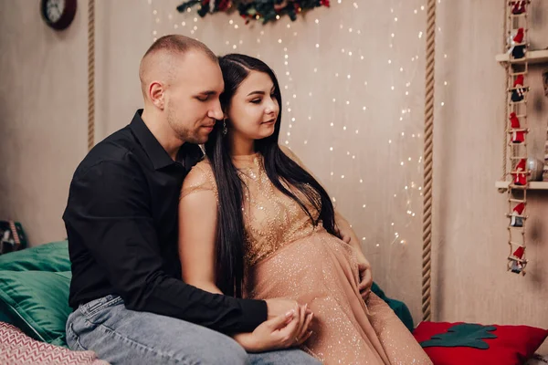 남자가 아기와 여자를 크리스마스 침대에 키스하며 새해를 축하하고 임산부가 아기를 — 스톡 사진