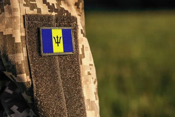 stock image Close up millitary woman or man shoulder arm sleeve with Barbados flag patch. Barbados troops army, soldier camouflage uniform. Armed Forces, empty copy space for text
