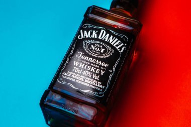 Khmelnytskyi, Ukrayna - 22 Kasım 2022: Glass bottle of American brand of New Tennessee Whiskey Jack Daniel 's, Jack Daniel Distillery on red and blue background, copy space. En çok satan alkol