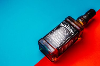 Khmelnytskyi, Ukrayna - 22 Kasım 2022: Glass bottle of American brand of New Tennessee Whiskey Jack Daniel 's, Jack Daniel Distillery on red and blue background, copy space. En çok satan alkol