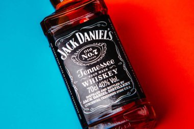 Khmelnytskyi, Ukrayna - 22 Kasım 2022: Glass bottle of American brand of New Tennessee Whiskey Jack Daniel 's, Jack Daniel Distillery on red and blue background, copy space. En çok satan alkol