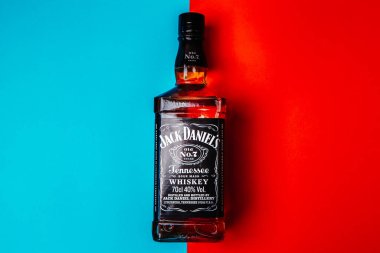 Khmelnytskyi, Ukrayna - 22 Kasım 2022: Glass bottle of American brand of New Tennessee Whiskey Jack Daniel 's, Jack Daniel Distillery on red and blue background, copy space. En çok satan alkol