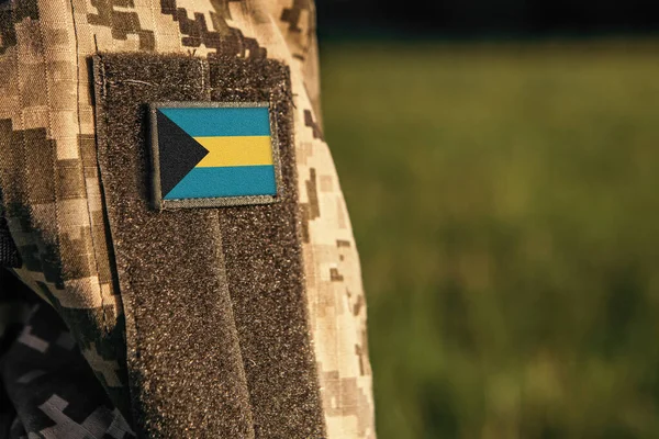 Close up millitary woman or man shoulder arm sleeve with Bahamas flag patch. Bahamas troops army, soldier camouflage uniform. Armed Forces, empty copy space for text