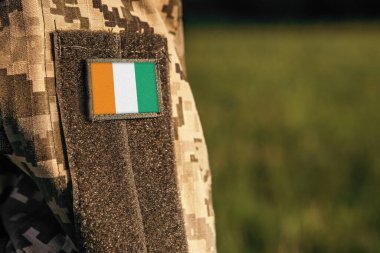 Cote d 'Ivoire Fildişi Sahil Bayraklarıyla askeri kadın ya da erkek omuz kolunu kapat. Asker ordusu, asker kamuflaj üniforması. Silahlı Kuvvetler, metin için boş kopyalama alanı