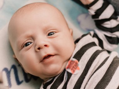 Little boy cute child lying in baby carriage pram buggy having fun smiling laughing, playing making faces grimaces. Toddler playful baby have a walk with mother. Happy childhood. Family concept