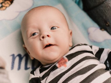 Little boy cute child lying in baby carriage pram buggy having fun, playing making faces grimaces. Toddler playful baby have a walk with mother. Happy childhood. Family concept