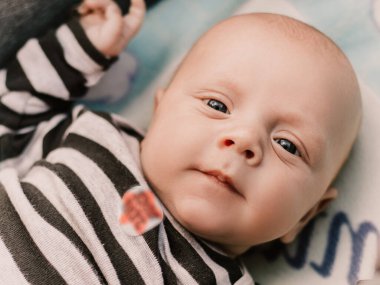 Little boy cute child lying in baby carriage pram buggy having fun smiling laughing, playing making faces grimaces. Toddler playful baby have a walk with mother. Happy childhood. Family concept