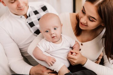 Little boy happy funny surprised cute child baby playing with parents, sitting on knees. Playful shocked toddler with bulging eyes having fun, making faces grimaces. Happy childhood, family concept