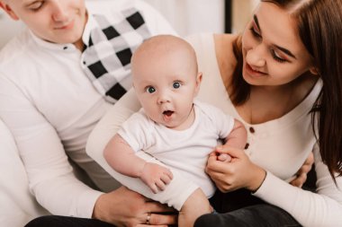 Little boy happy funny surprised cute child baby playing with parents, sitting on knees. Playful shocked toddler with bulging eyes having fun, making faces grimaces. Happy childhood, family concept