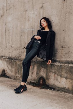 Pretty woman posing near gray wall. Girl dressed casual outfits with red lips. Fashion, make up, hairstyle