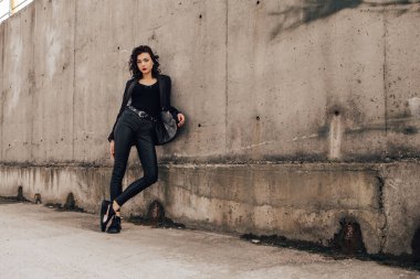 Pretty woman posing near gray wall. Girl dressed casual outfits with red lips. Fashion, make up, hairstyle