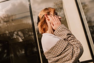 Pretty woman posing near glass building. Girl dressed casual outfits with red lips. Fashion, make up, hairstyle