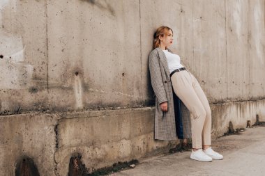 Pretty woman posing near gray wall. Girl dressed casual outfits with red lips. Fashion, make up, hairstyle