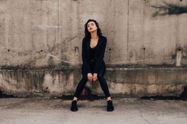 Pretty woman posing near gray wall. Girl dressed casual outfits with red lips. Fashion, make up, hairstyle