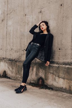 Pretty woman posing near gray wall. Girl dressed casual outfits with red lips. Fashion, make up, hairstyle