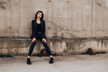 Pretty woman posing near gray wall. Girl dressed casual outfits with red lips. Fashion, make up, hairstyle