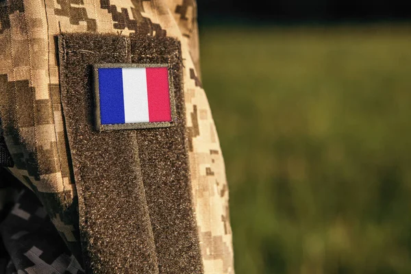 Close up millitary woman or man shoulder arm sleeve with France flag patch. France troops army, soldier camouflage uniform. Armed Forces, empty copy space for text