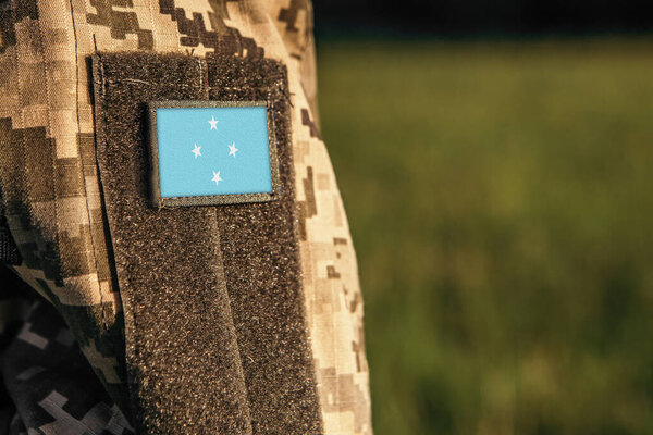 Закройте рукав женского или мужского плеча с пластырем под флагом Микронезии. Армия Микронезии, солдатская камуфляжная форма. Вооруженные силы, свободное место для копирования текста