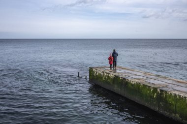 Odessa, Ukrayna 19.02.2023. İnsanlar Ukrayna 'nın Odessa kentindeki Lanzheron plajında bulutlu bir kış günü deniz kenarında yürür.