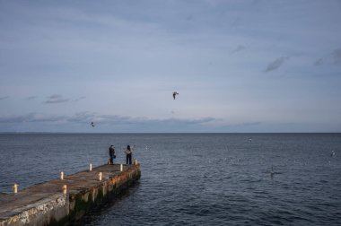 Odessa, Ukrayna 19.02.2023. İnsanlar Ukrayna 'nın Odessa kentindeki Lanzheron plajında bulutlu bir kış günü deniz kenarında yürür.