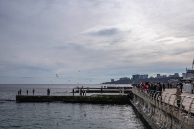 Odessa, Ukrayna 19.02.2023. İnsanlar Ukrayna 'nın Odessa kentindeki Lanzheron plajında bulutlu bir kış günü deniz kenarında yürür.