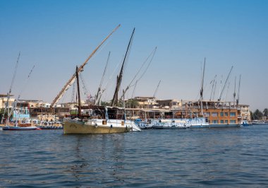 Luxor, Mısır - 27.07.2025. Nil Nehri manzaralı kıyı şeridi boyunca oteller ve binalar ve açık mavi bir gökyüzü.