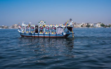 Luxor, Mısır - 27.07.2025. Geleneksel Felucca yelkenli tekneleri ve diğer tur tekneleri Nil Nehri 'ndeki kalabalık bir rıhtıma yanaştı, turistler için hazırlar.
