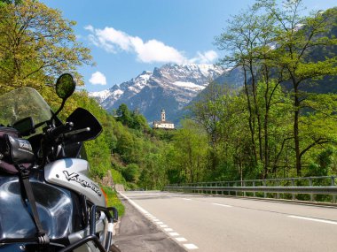 Mesocco, Switzerland - May 5, 2018: Church of Santa Maria del Castello with parked motorcycle.