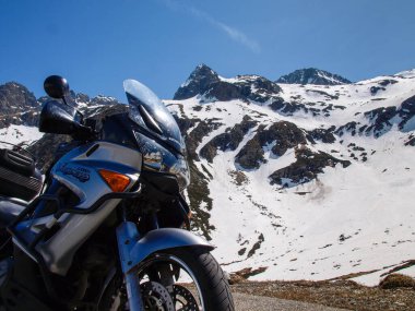 Pass of Spluga, Italy - May 5, 2018: alpine landscape and parked motorcycle
