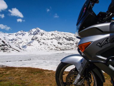 Pass of Spluga, Italy - May 5, 2018: alpine landscape and parked motorcycle