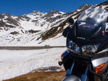 Pass of Spluga, Italy - May 5, 2018: alpine landscape and parked motorcycle