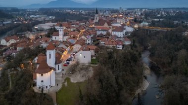 Aerial shot of the Kranj city center with the church and the river Kokra flowing throu the canyon in the evening, Slovenia clipart