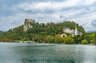 Slovenya 'da bulutlu bir yaz sabahı, uçurumun tepesinde bir şato ve St. Martin (Sveti Martin) kilisesi kanadı.