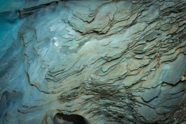 Striated rock face. Blue-grey stone layers form abstract patterns.