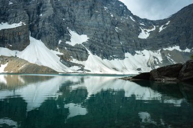 A stunning scene of a mountain reflected in a lake, with snow-covered peaks