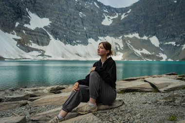 Woman enjoying the peaceful lake view with snow-capped mountains in the background