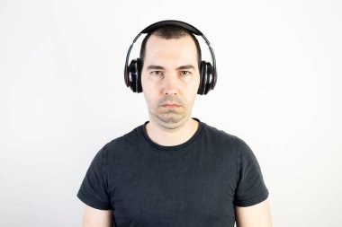 Genç erkek manken kulaklık takıyor. Havalı moda tarzı. Mutsuz görünüyor..