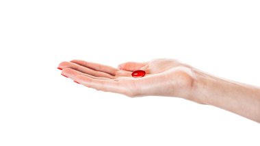 Beyaz arka planda izole edilmiş kırmızı bir kapsül tutuyor. Kırmızı hap izole edildi. Yüksek kalite fotoğraf