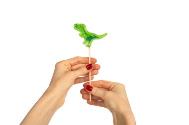 Beyaz arka planda izole edilmiş kadın eli lolipopu. Dinozor şeklinde lolipop. Kırmızı manikür. Chupa Chup 'lar. Yüksek kalite fotoğraf