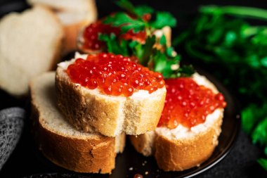 Koyu arkaplanda kırmızı havyar. Siyah üzerine kırmızı havyarlı sandviçler. Yüksek kalite fotoğraf
