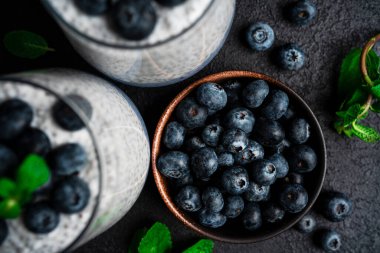 Arka planda yaban mersinli Chia pudingi. Siyah arka planda Chia pudingi, nane ve yaban mersini. Yüksek kalite fotoğraf