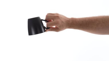 Bir el parlak bir arka planda sade bir kahve fincanını tutuyor. Kupanın basit tasarımı ışıkla çelişiyor, şeklini ve tutuş hareketini vurguluyor..