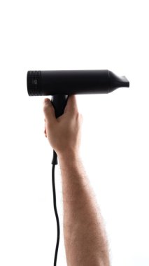 Biri parlak siyah bir saç kurutma makinesini beyaz bir arka plana doğru tutuyor. Cihaz modern ve güçlü görünüyor, saç şekillendirmek için ideal. Odak noktası el ve saç kurutma makinesi..