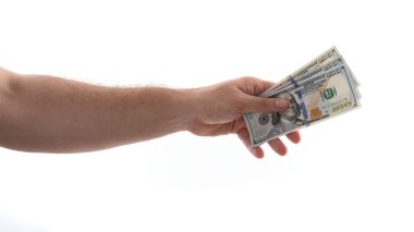 Bir el, bir kaç para destesini teslim etmek için uzanıyor. Arkaplan düz beyaz, işlemin gerçekleştiğini vurguluyor. Eylem, bir değişim ve mali etkileşim hissi veriyor.