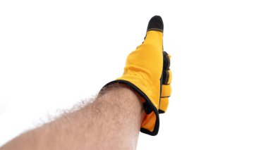 Parlak sarı bir eldiven giyen bir el, düz beyaz bir arka plana karşı baş parmak işareti verir. Jest pozitifliği ve onayı basit ama etkili bir şekilde iletir..