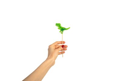 Beyaz arka planda izole edilmiş kadın eli lolipopu. Dinozor şeklinde lolipop. Kırmızı manikür. Chupa Chup 'lar. Yüksek kalite fotoğraf