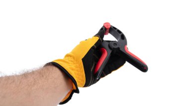 Sarı iş eldiveni takan bir elin elinde siyah ve kırmızı klemp aleti var. Arka plan beyaz, kıskaç detaylarını vurguluyor ve insan tutuşu, bir projeye hazır olduğunu gösteriyor..