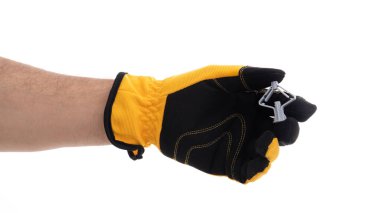 Siyah ve sarı güvenlik eldiveni takan bir el, çeşitli görevlerde çalışırken korunmak için kullanılan ekipmanları gösteren bir metal klipsi sıkıca tutar. Arkaplan tarafsız.